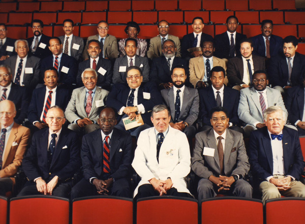 Group of men and one woman seated in rows of an auditorium.