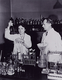 Dr. Gerty Cori, a White female holding up a test tube, and her husband Carl Cori in the laboratory at Washington University School of Medicine, St. Louis, 1947.